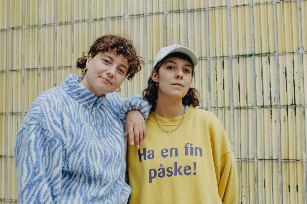 2 Girls 1 Club smiling for a picture together.