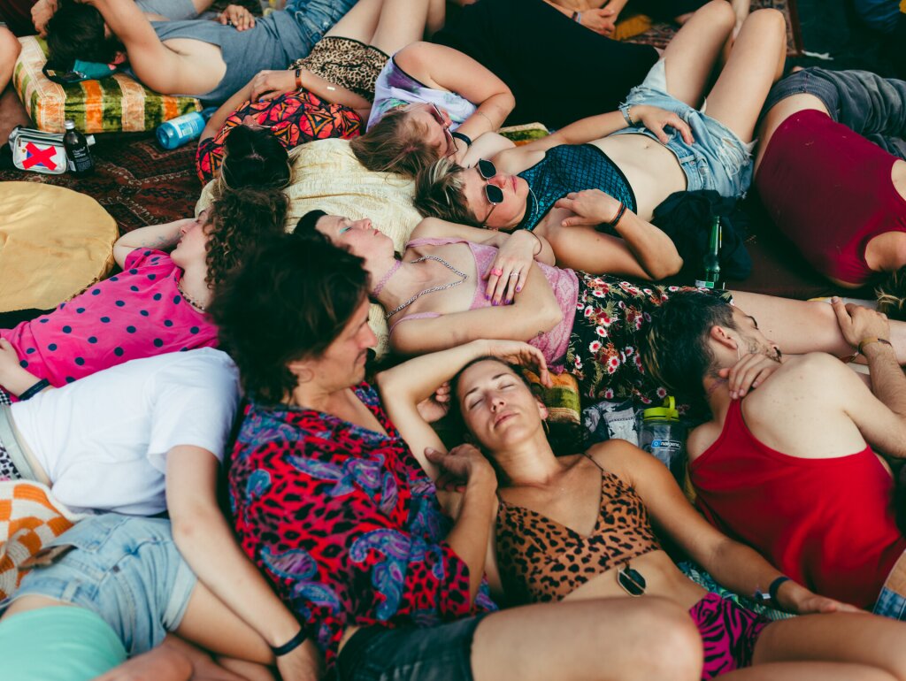 A group of people in colourful summer clothes relaxing and sleeping in the sun.