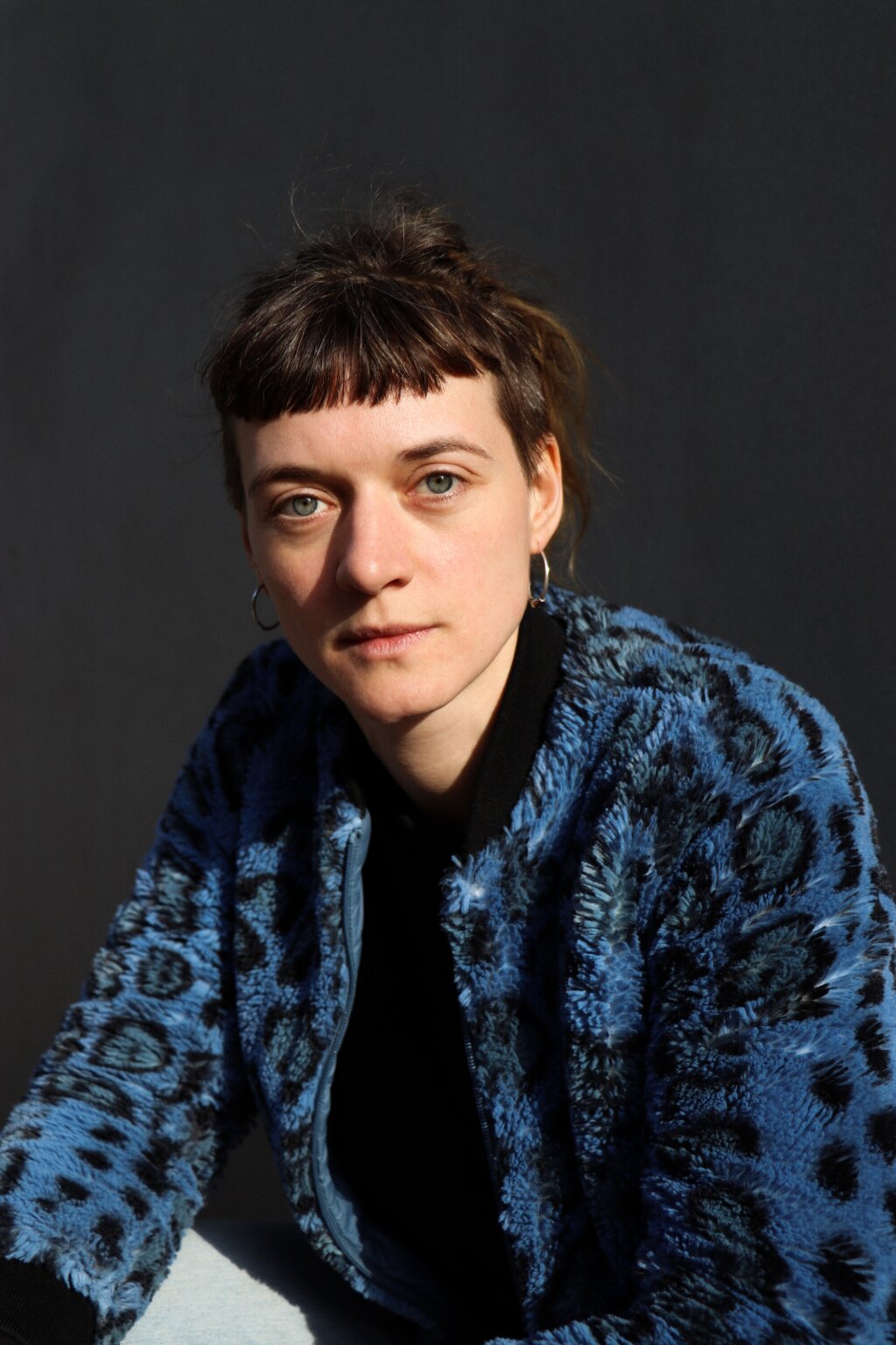 Portrait of the DJ PullenPenny wearing a blue Leo jacket.