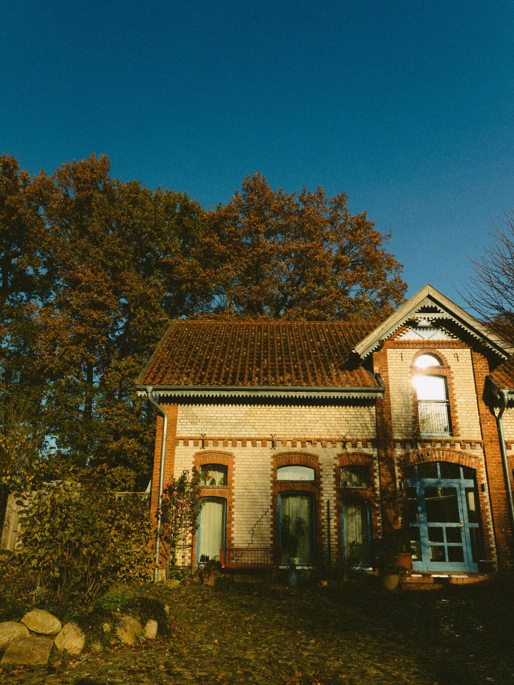 A country house with an autumnal sky and trees in the background.